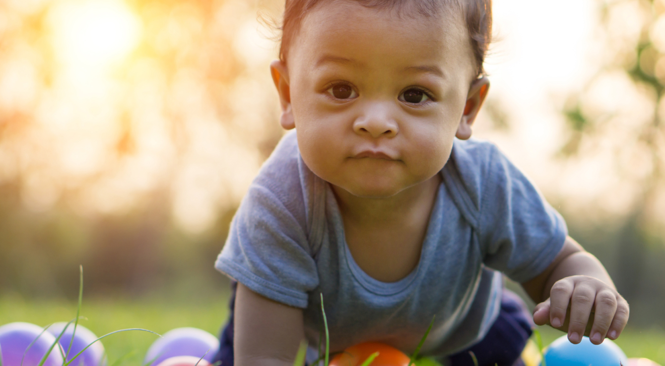 Un bebé gateando entre pelotas de juguete en el exterior