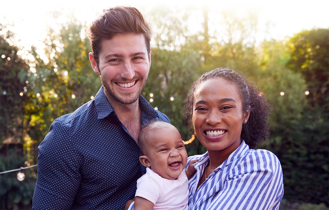 Padre, madre y bebé interraciales sonriendo juntos