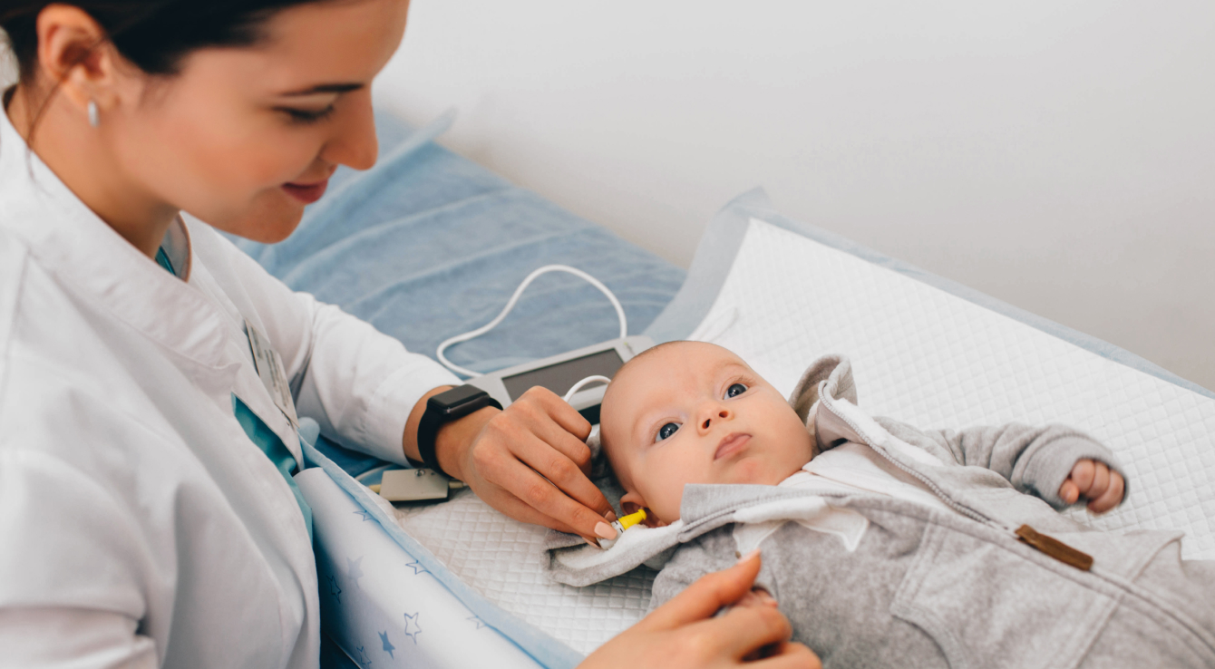 Médico examinando a un bebé y realizando una prueba de audición