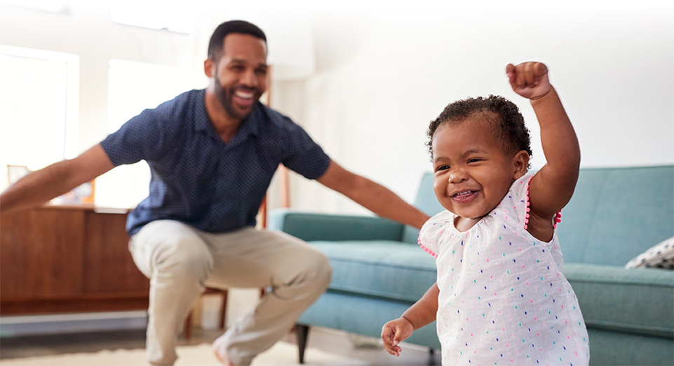 Father and toddler daughter dancing together in the living room