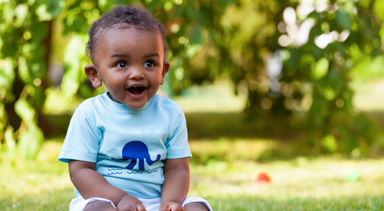 Toddler boy smiling and sitting in grass