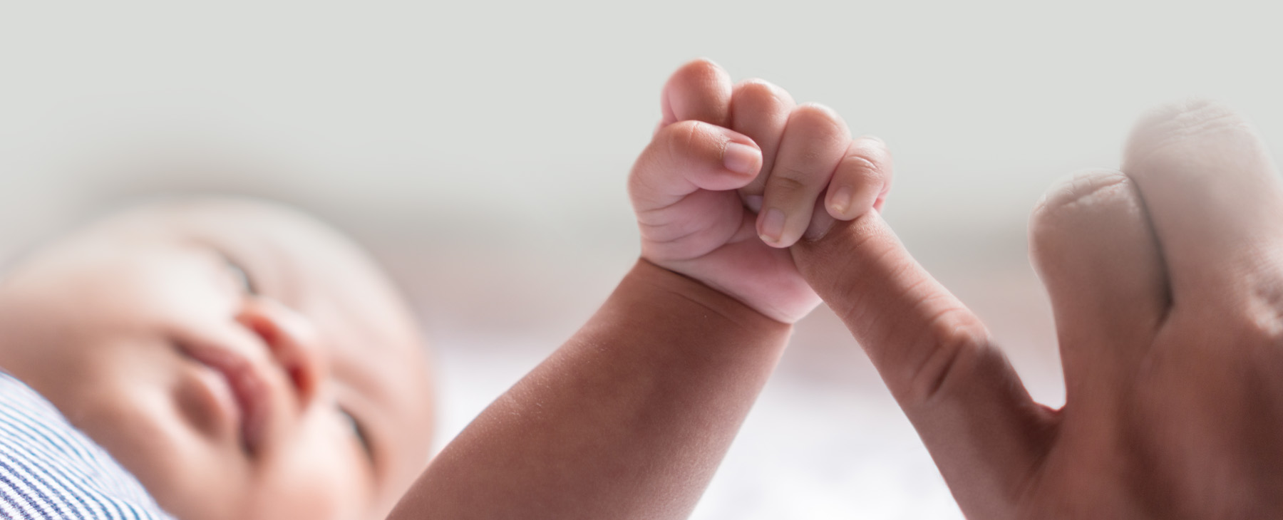 Newborn baby holding onto father's finger